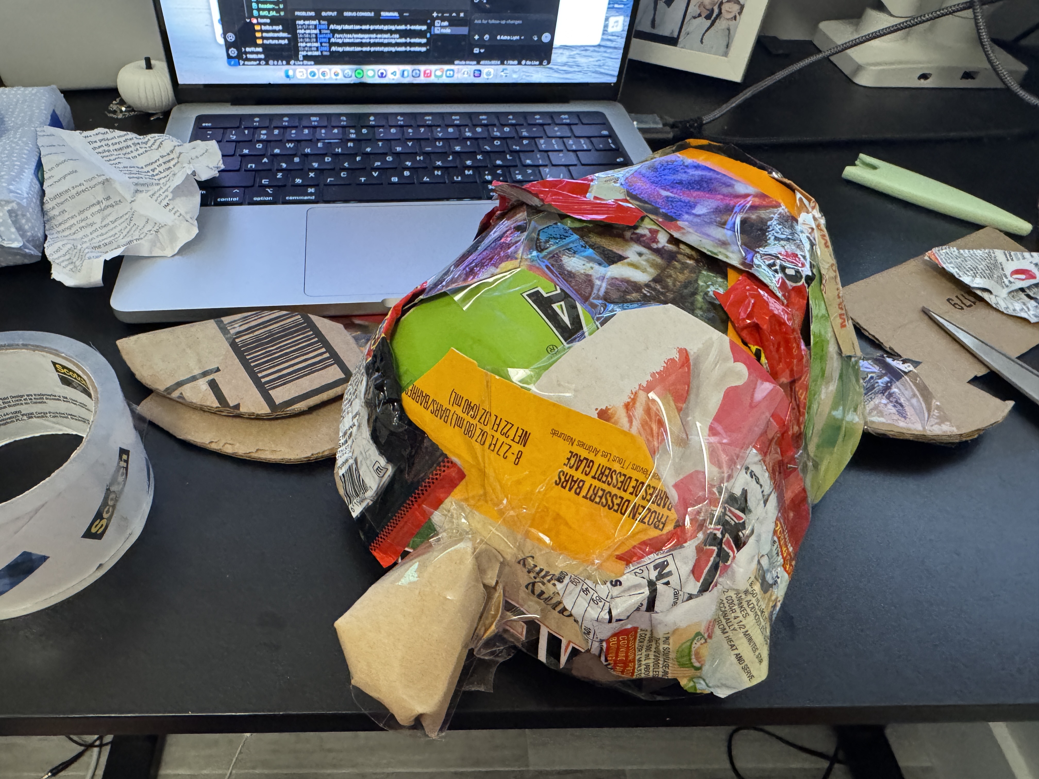 Turtle sculpture with colorful packaging covering most of the shell and cardboard flippers being attached.