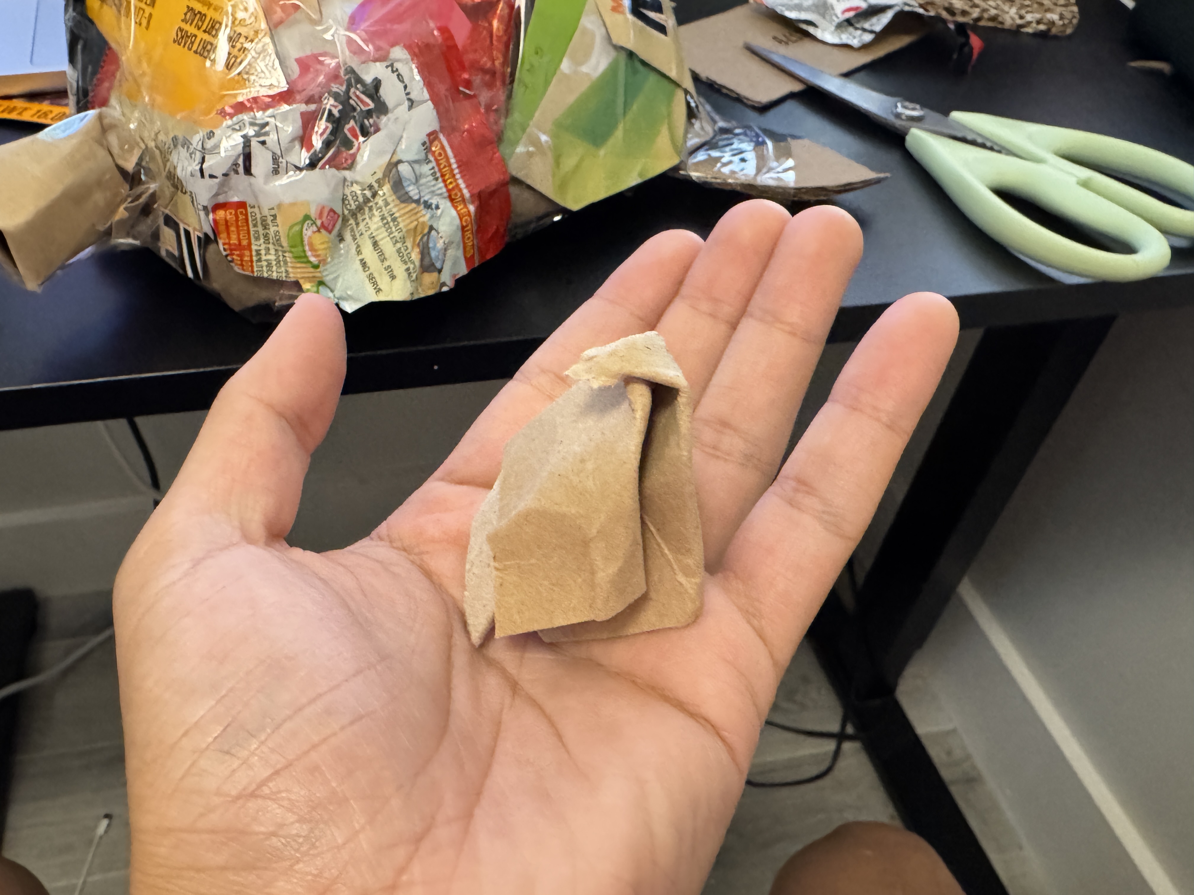 Small folded brown paper form held in a hand as an early material experiment.