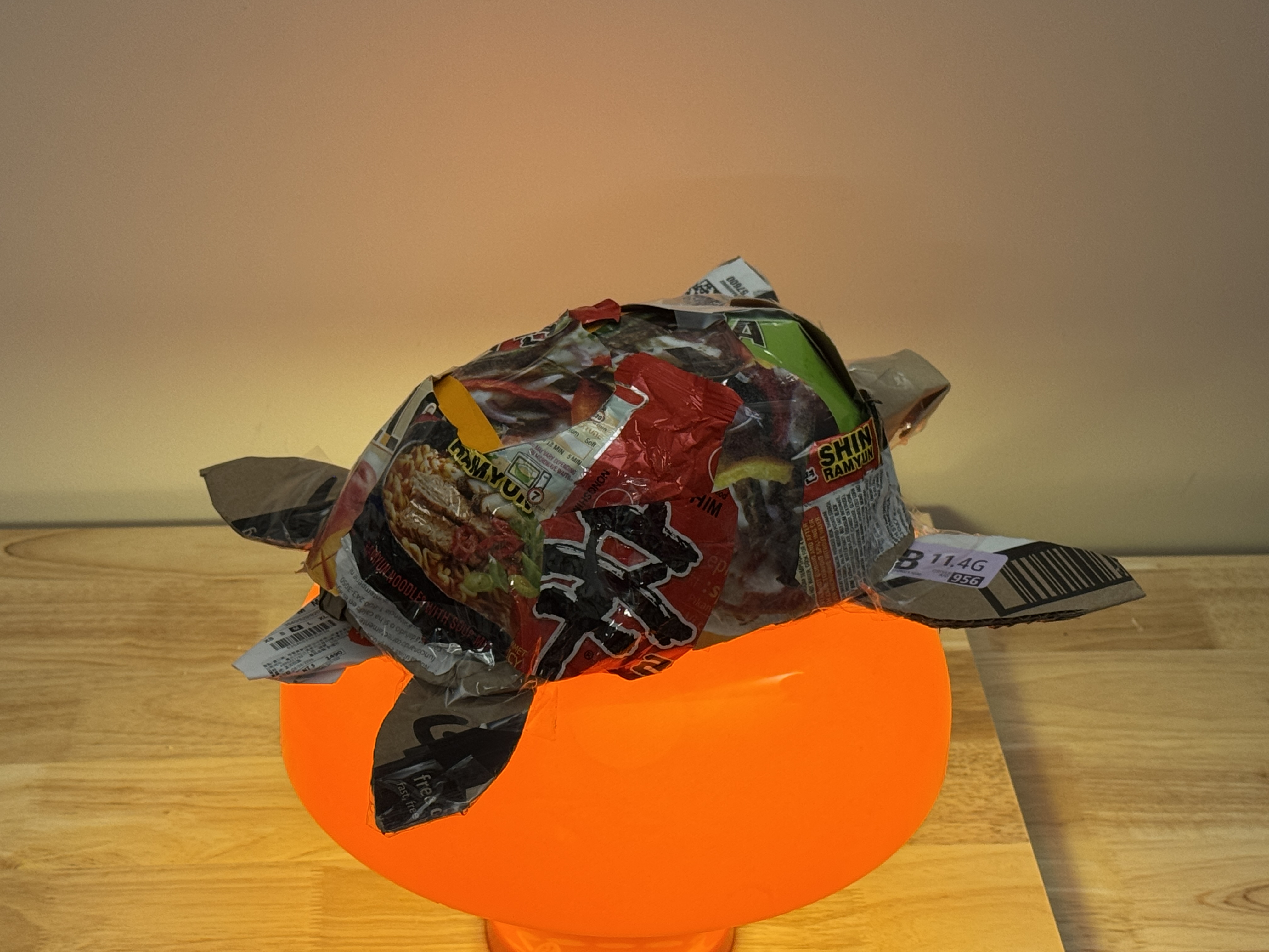 Recycled-material turtle sculpture resting on an orange glowing light.