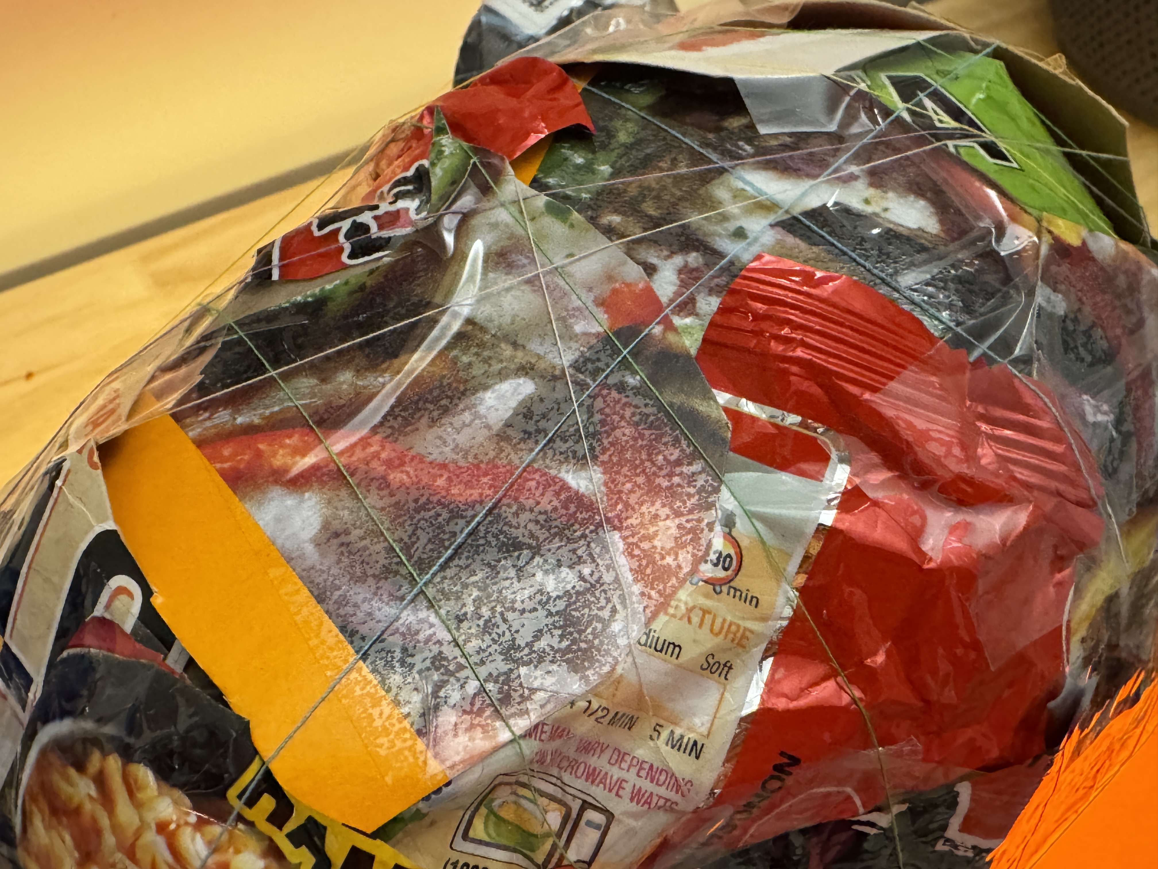 Close-up of colorful food packaging layered across the turtle shell with thin thread crossing over it.
