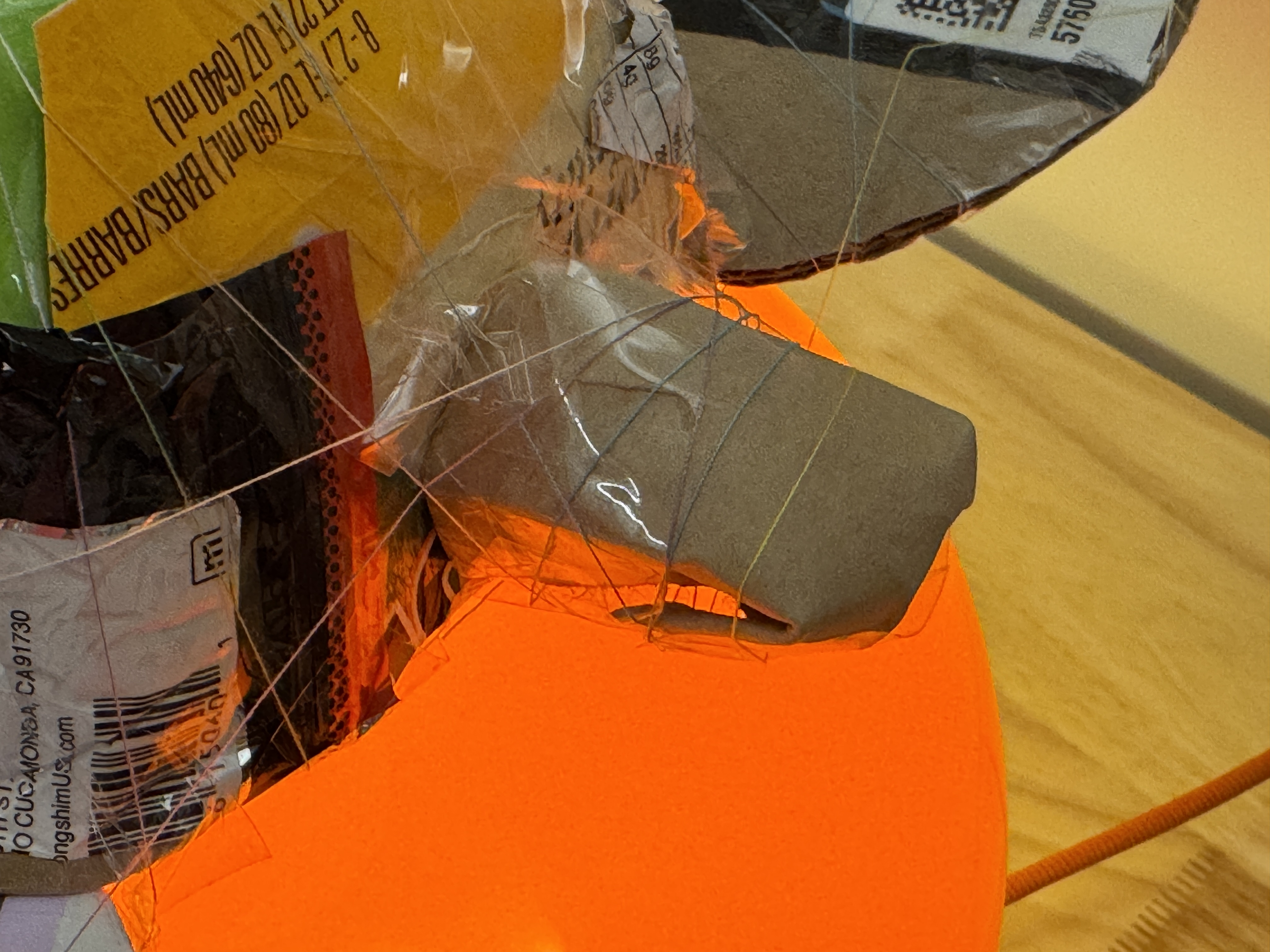 Close-up of a cardboard flipper and turtle body wrapped with thin thread.