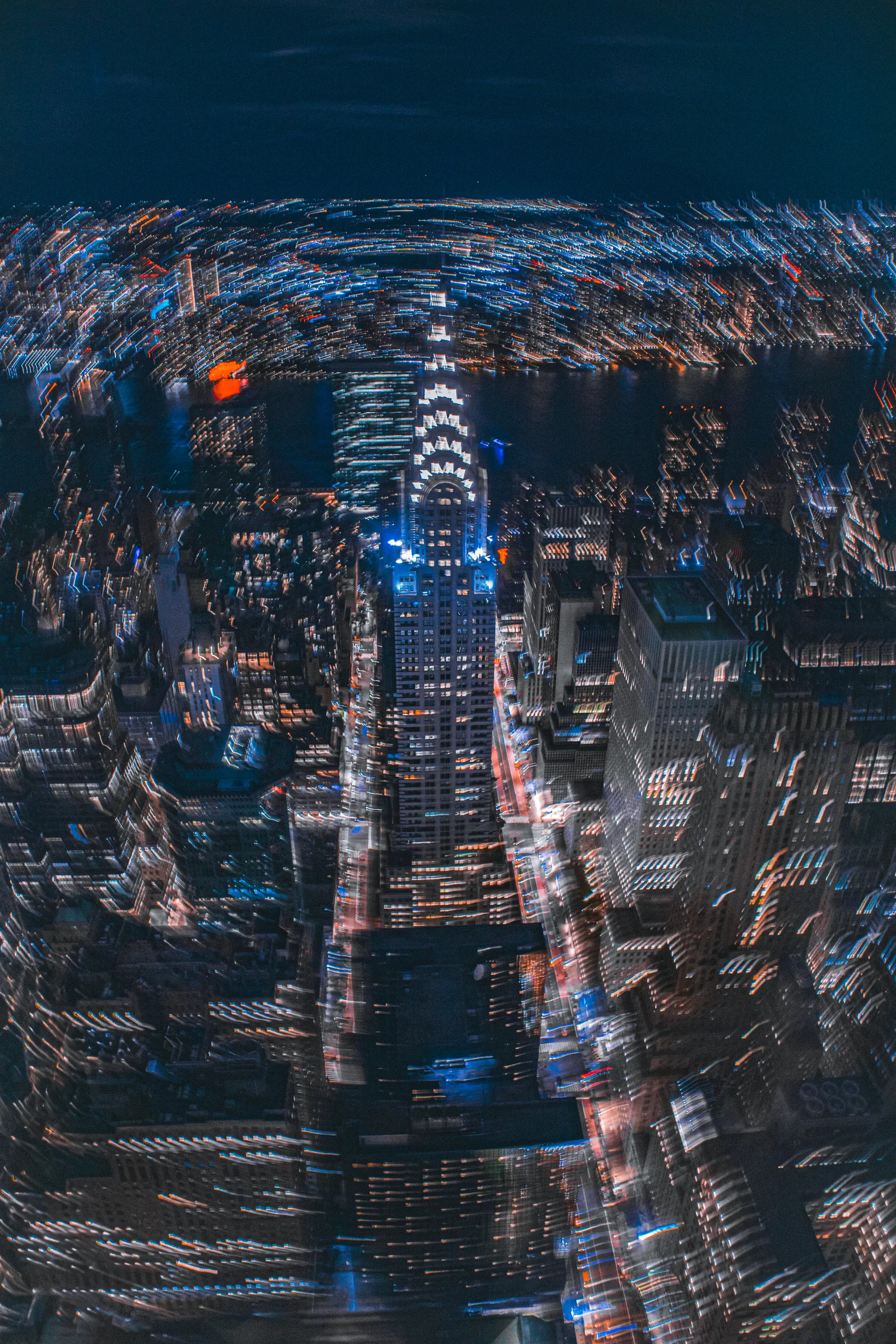Looking down over illuminated Manhattan streets and the Chrysler Building at night.