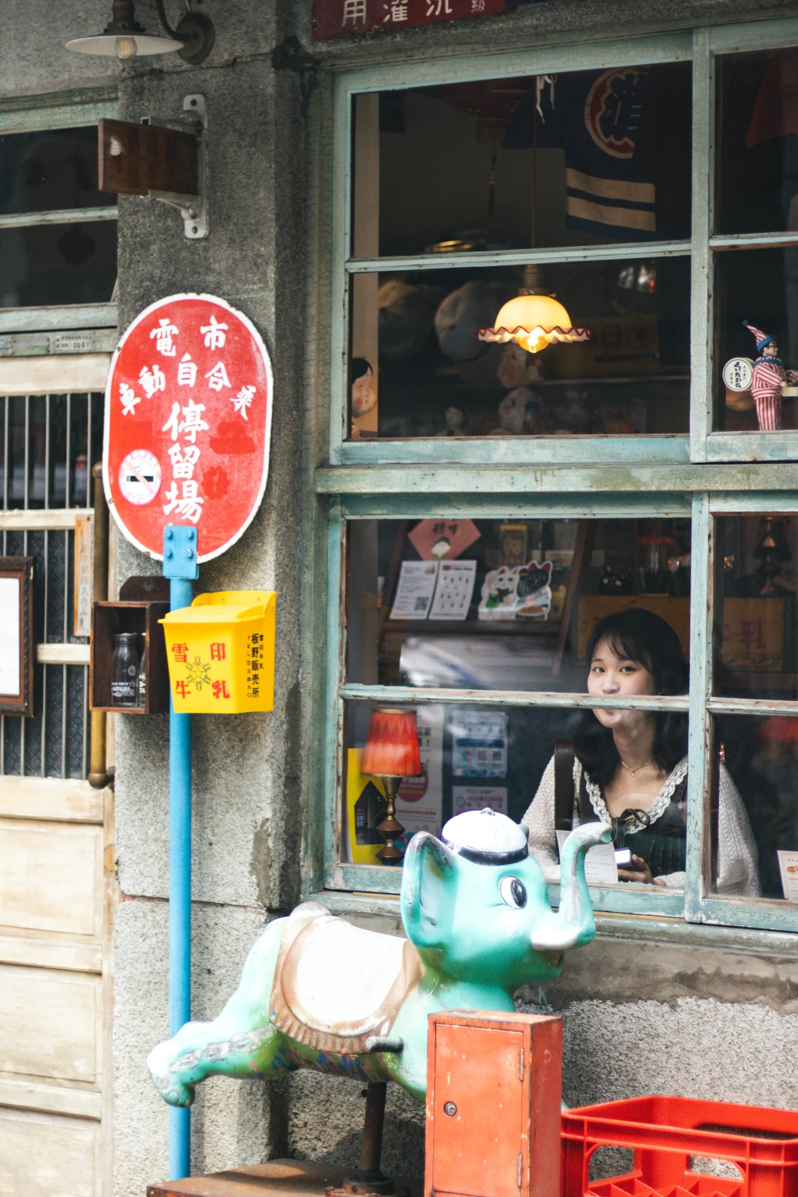 Colorful signs and small decorations surround a green-framed shop window.