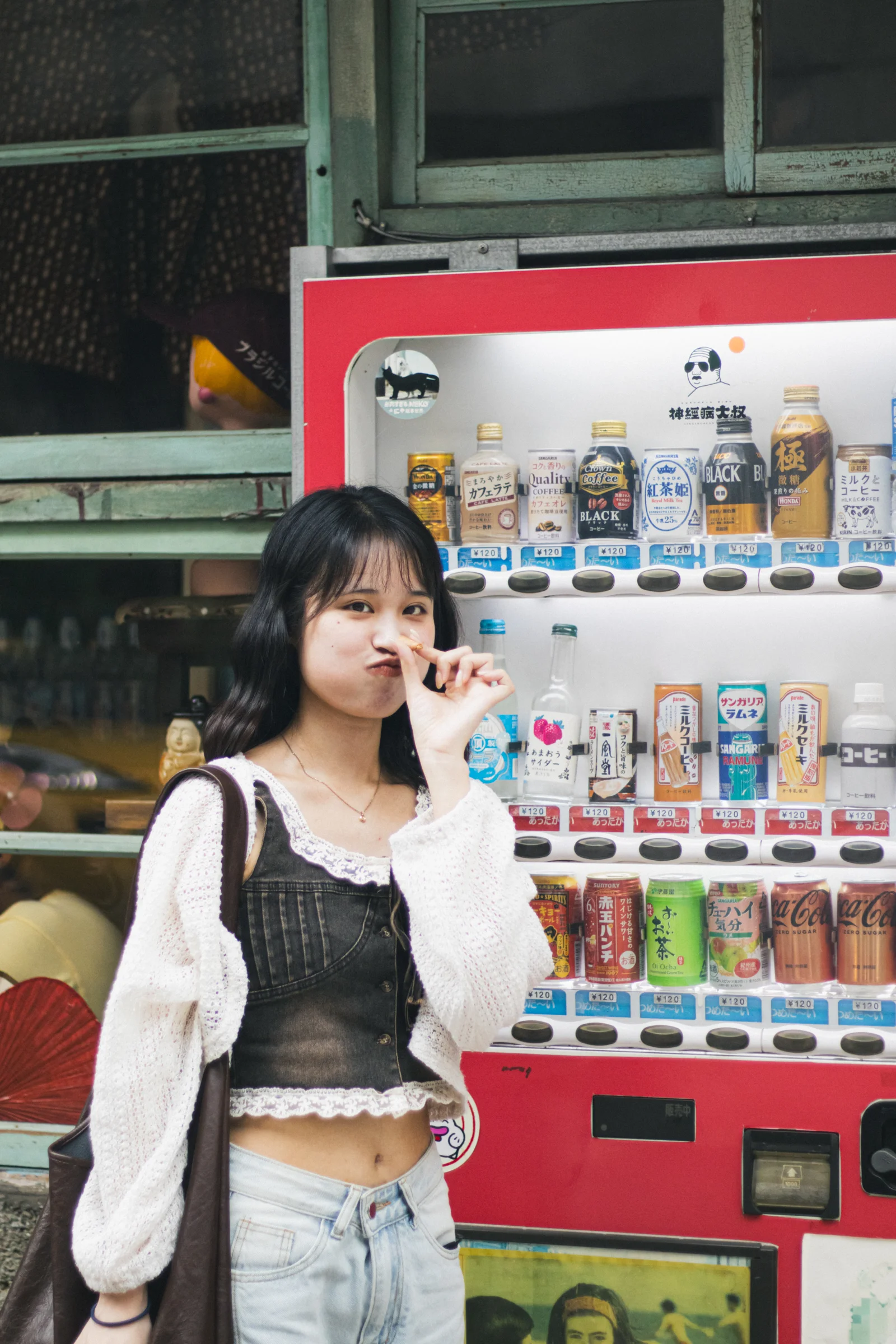 A person holding an ice cream stands in front of a red vending machine.