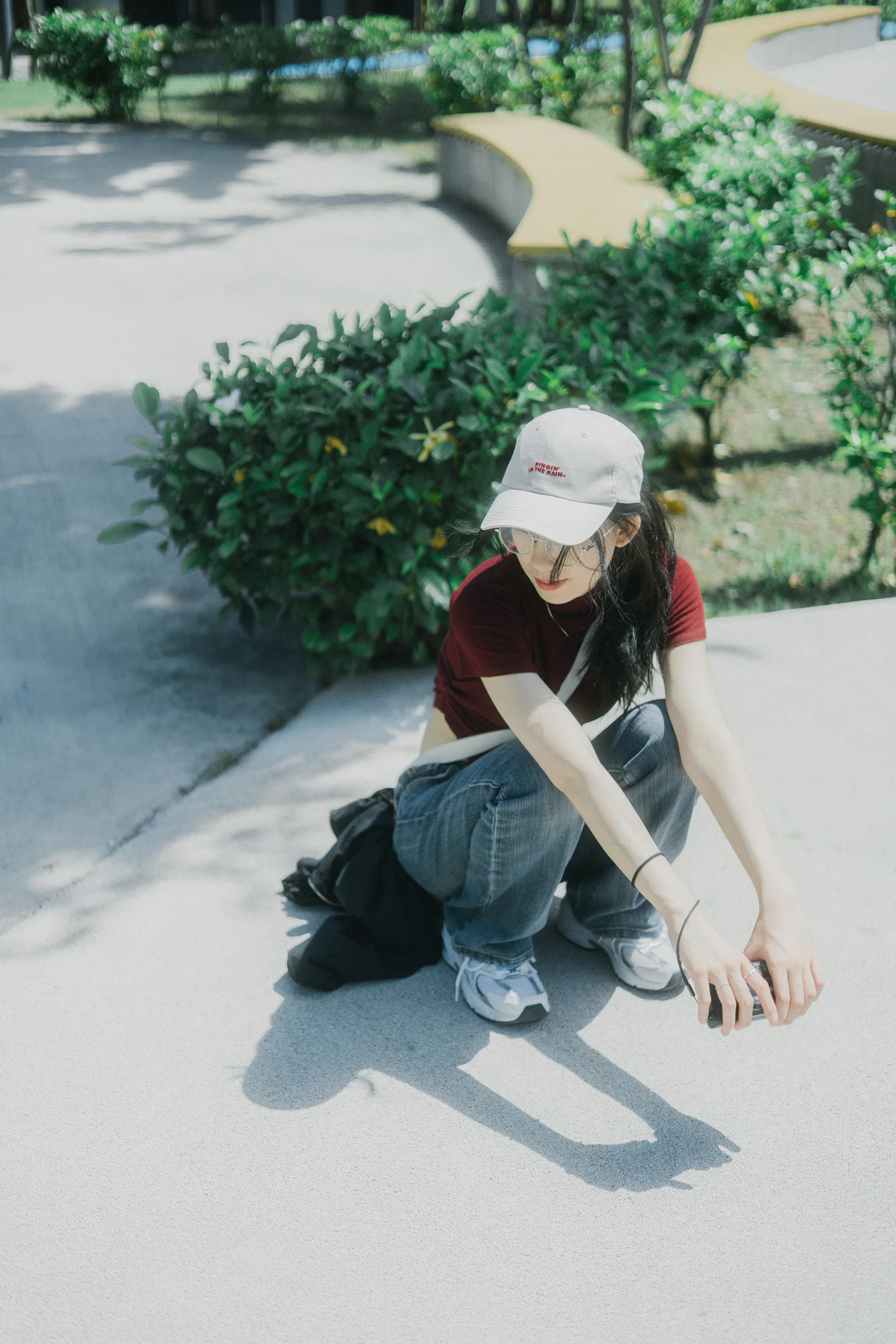 A person wearing a white cap crouches beside a curved garden path.