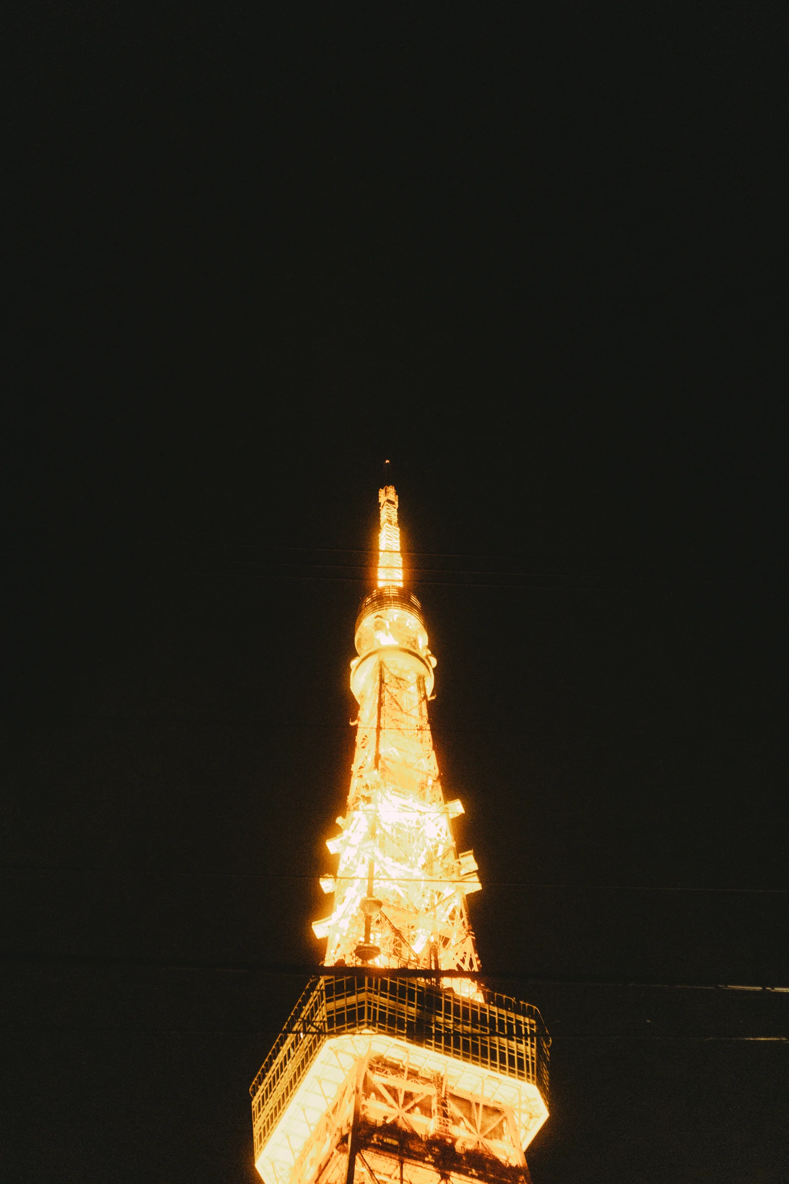 Tokyo Tower shines gold against a dark night sky.