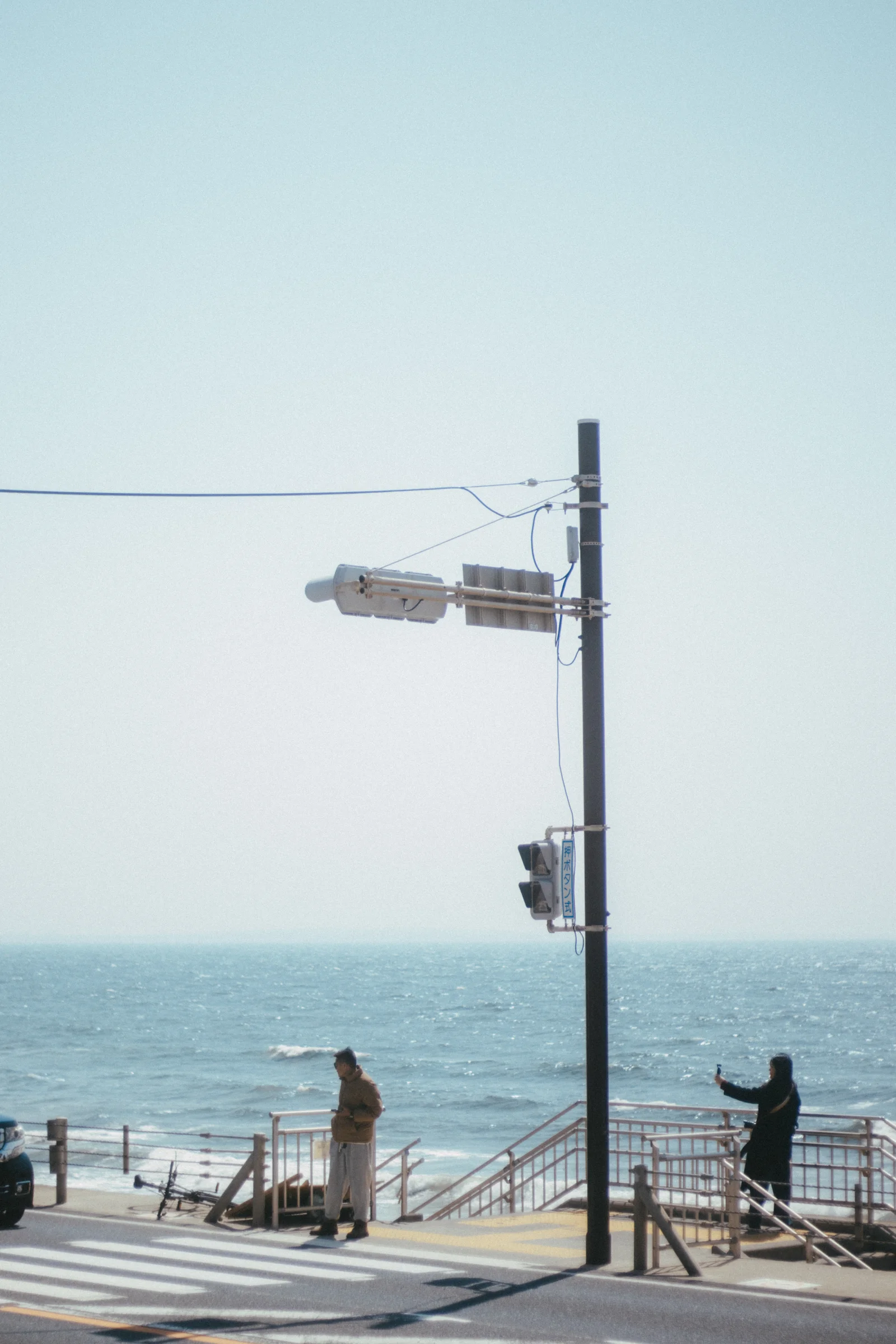 A coastal road and traffic signal overlook a bright blue sea.