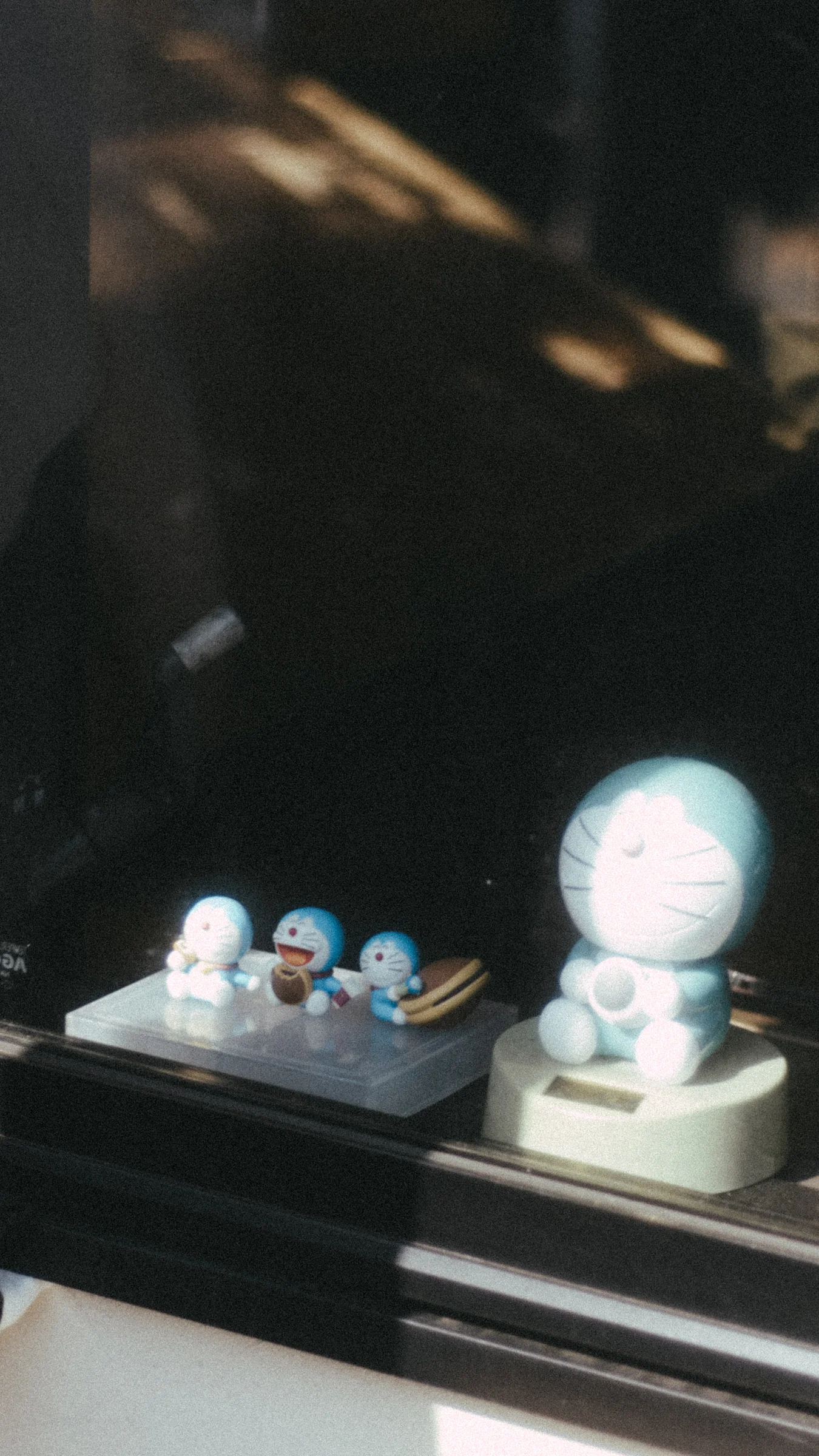Small ornaments catch the light in a dark shop window.