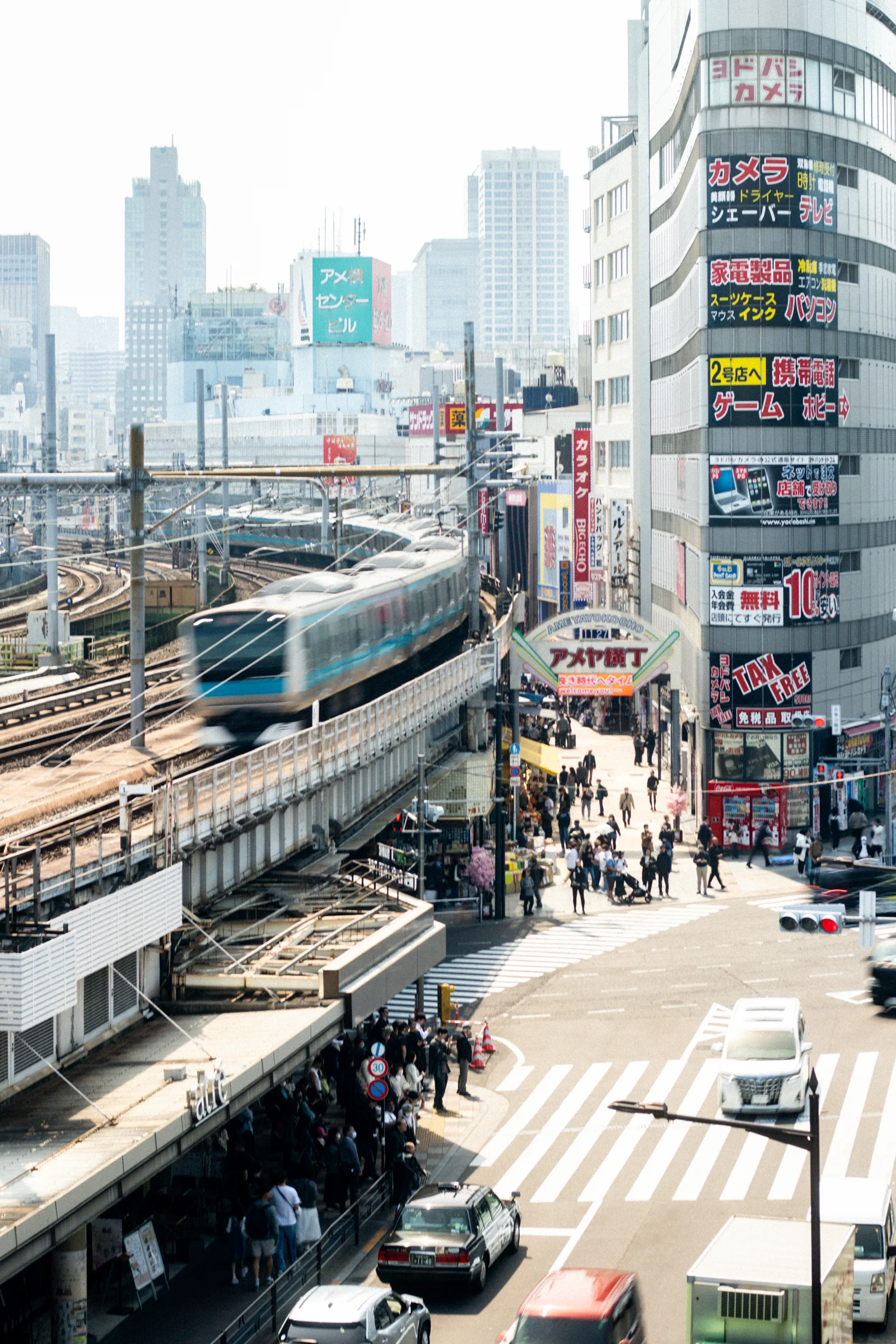 A train travels along elevated tracks between dense city buildings.