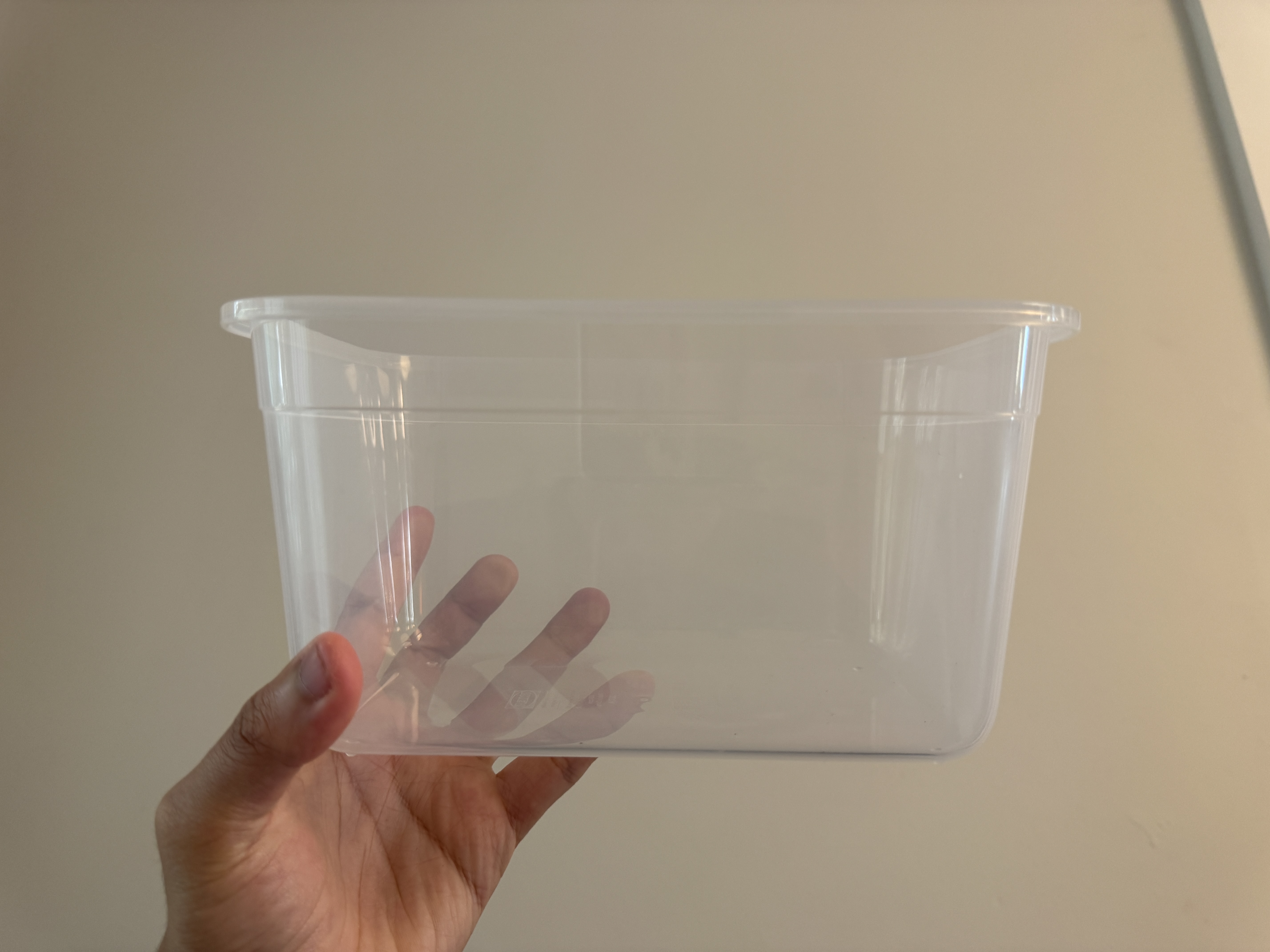 A hand holding the empty transparent plastic container used for the prototype.