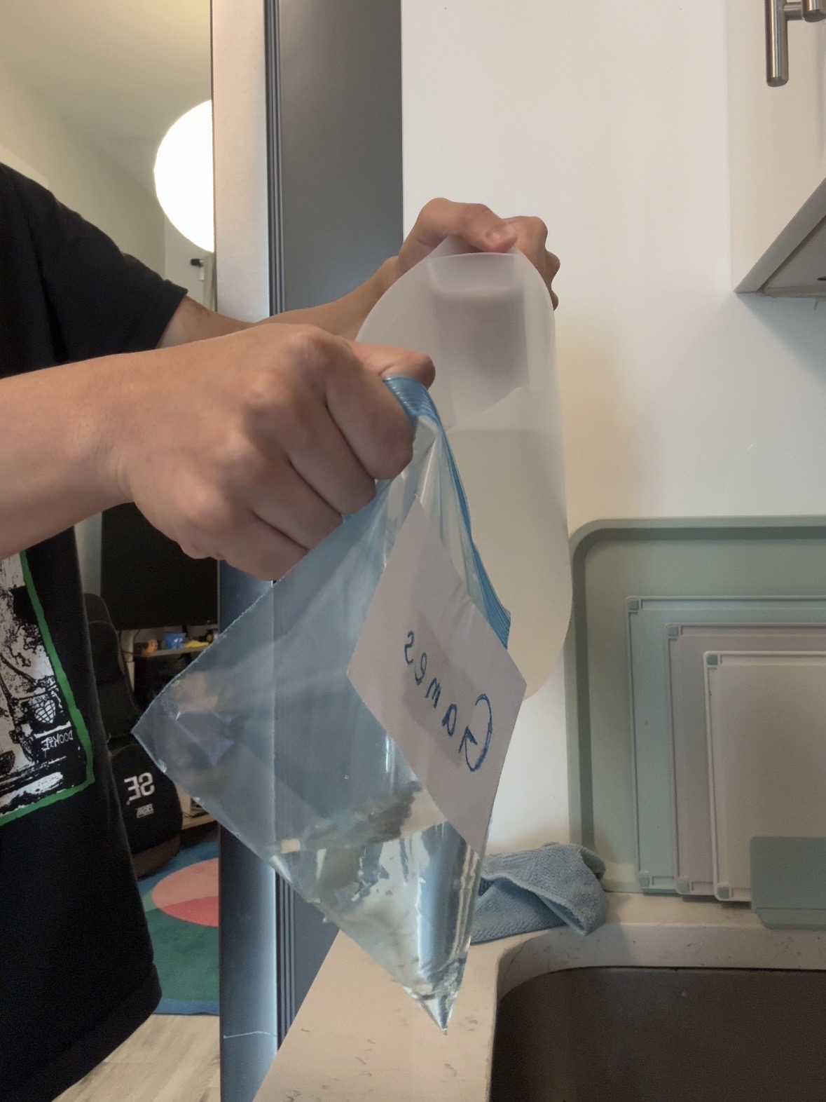 A person pours water from a translucent pitcher into a zip-top bag labeled Games.
